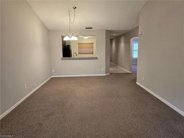 Living room featuring carpet floors, lofted ceiling, a textured ceiling, and a chandelier