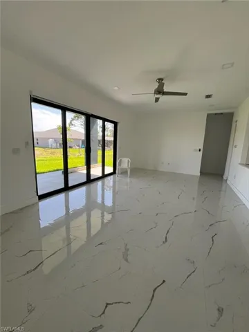 Spare room with light marble finish flooring, a ceiling fan, and a residential view