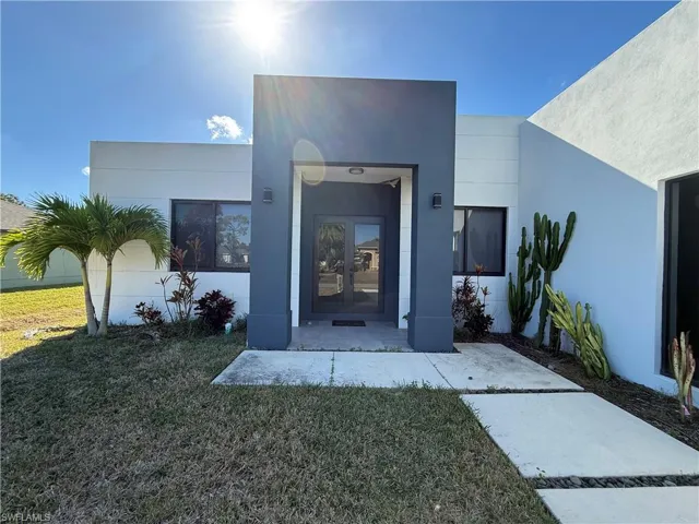 Property entrance with a yard, stucco siding, and french doors