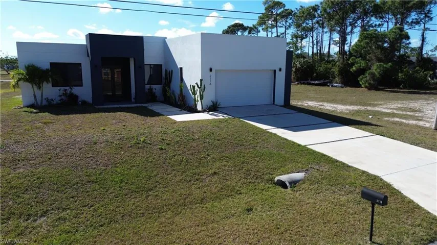 Contemporary house with stucco siding, an attached garage, concrete driveway, and a front yard
