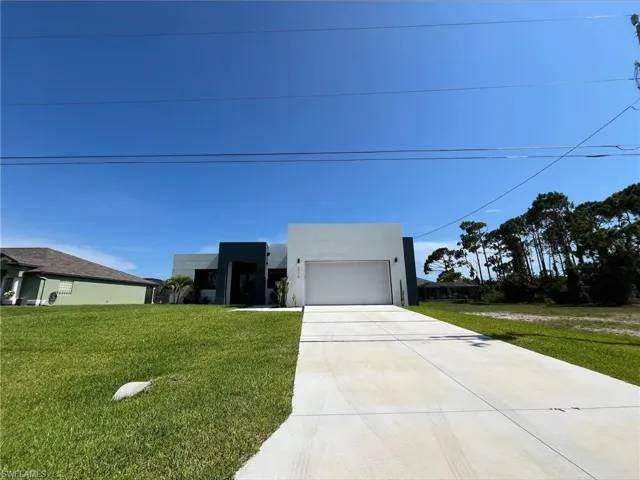 Contemporary home with concrete driveway, a front lawn, stucco siding, and an attached garage