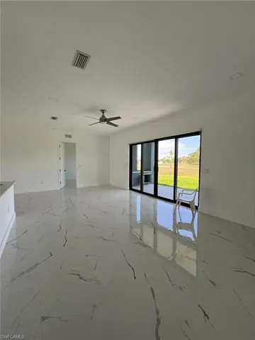 Unfurnished room featuring light marble finish flooring and ceiling fan