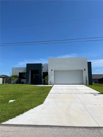 Modern home featuring stucco siding, driveway, a front lawn, and a garage