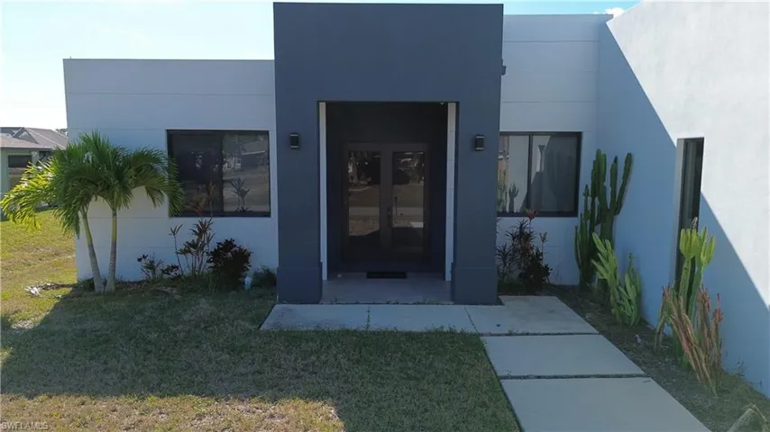 Entrance to property featuring stucco siding, a lawn, and french doors