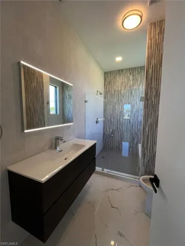 Bathroom featuring a shower stall, light marble finish flooring, and vanity