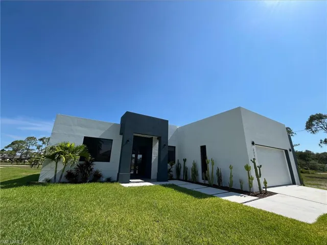 Contemporary home with a front yard, stucco siding, concrete driveway, and a garage