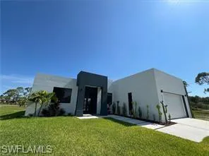 View of front facade with a front lawn, stucco siding, and driveway