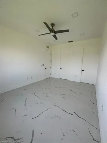 Unfurnished bedroom with ceiling fan, light marble finish floors, and a closet