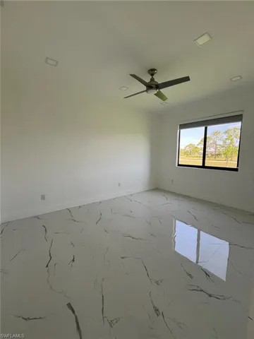 Empty room featuring light marble finish floors and a ceiling fan