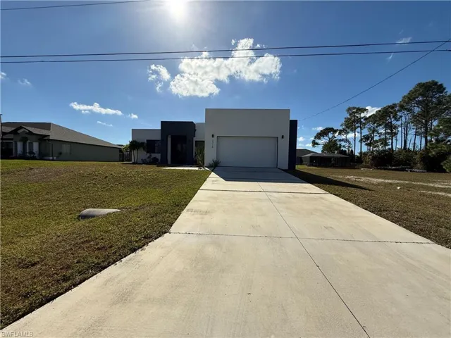 Modern home with a front yard, stucco siding, and concrete driveway