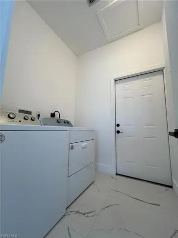 Laundry room with light marble finish floors, separate washer and dryer, and attic access