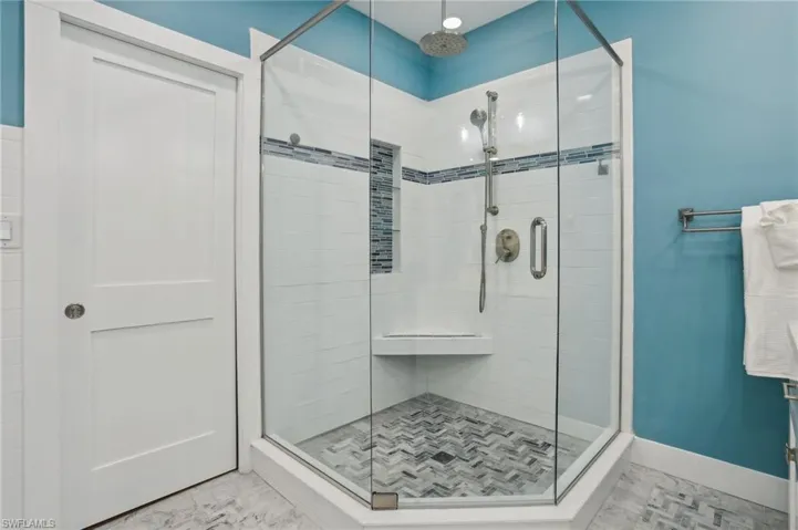 Bathroom with a shower with shower door and tile patterned floors