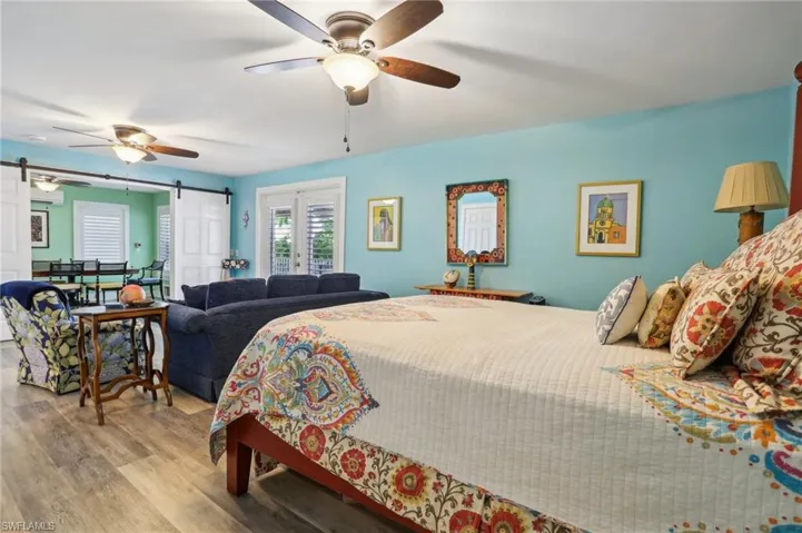 Bedroom featuring ceiling fan, light hardwood / wood-style flooring, and a barn door