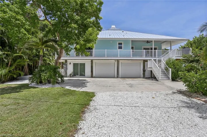 Coastal home featuring a porch, a garage, a front lawn, and ceiling fan