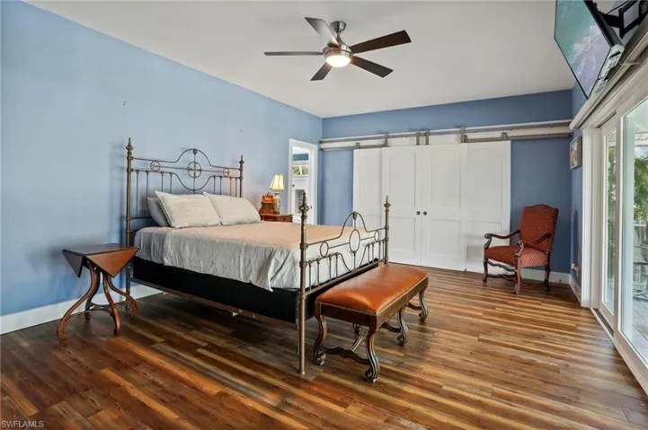 Bedroom featuring a barn door, wood-type flooring, ceiling fan, and access to exterior