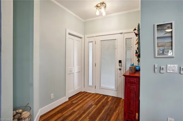 Foyer entrance featuring crown molding and dark hardwood / wood-style floors