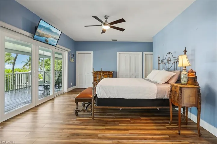 Bedroom with two closets, hardwood / wood-style flooring, access to exterior, and ceiling fan
