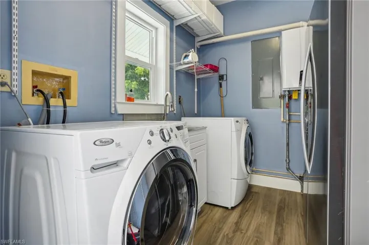 Washroom featuring washing machine and clothes dryer, electric panel, and hardwood / wood-style floors