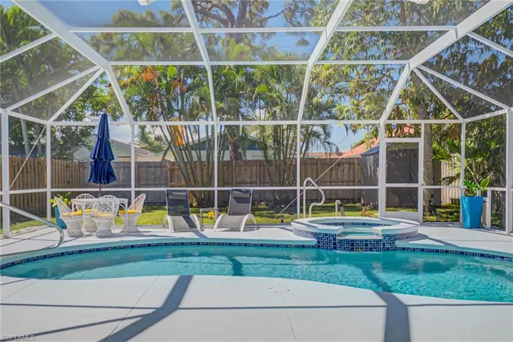 View of swimming pool with a lanai, a sunroom, a fenced backyard, a pool with connected hot tub, and a patio area
