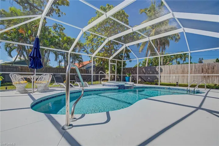 View of pool with a lanai, a patio, a fenced backyard, and a pool with connected hot tub