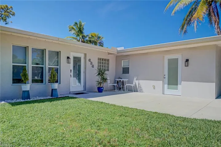 Doorway to property featuring stucco siding, a yard, and a patio