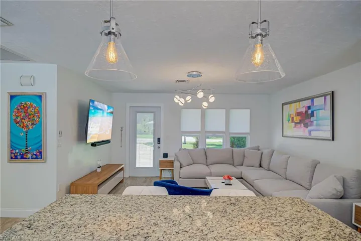Living area featuring light wood finished floors, a textured ceiling, and a chandelier
