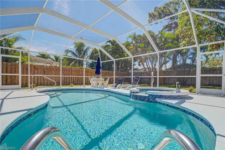 View of pool featuring glass enclosure, a fenced backyard, a pool with connected hot tub, a patio, and a sunroom