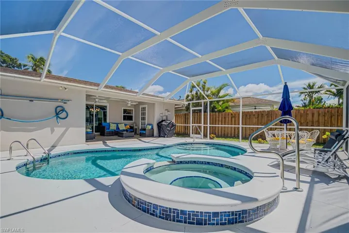 View of swimming pool featuring a patio, a ceiling fan, glass enclosure, and a pool with connected hot tub