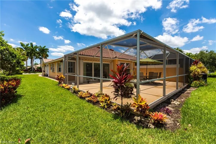 Back of house featuring a patio area, a lawn, and glass enclosure