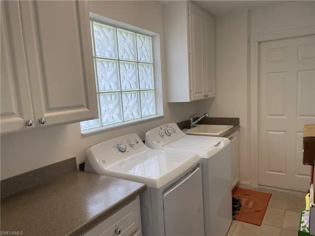 Clothes washing area featuring sink, independent washer and dryer, cabinets, and light tile patterned floors