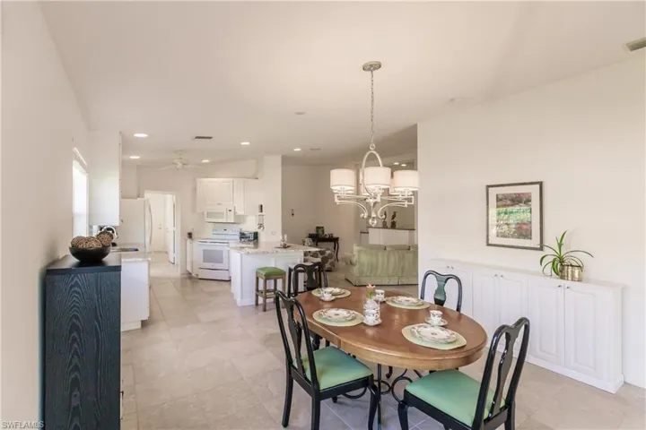 Dining room with light tile patterned floors and ceiling fan with notable chandelier