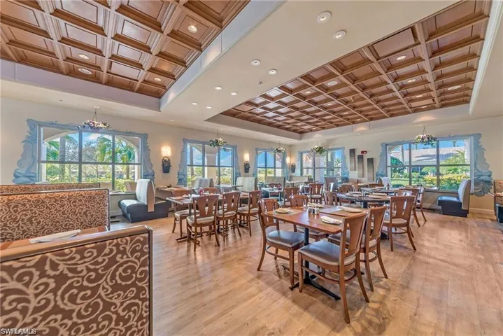 Dining space featuring a chandelier, coffered ceiling, light wood-type flooring, and a raised ceiling