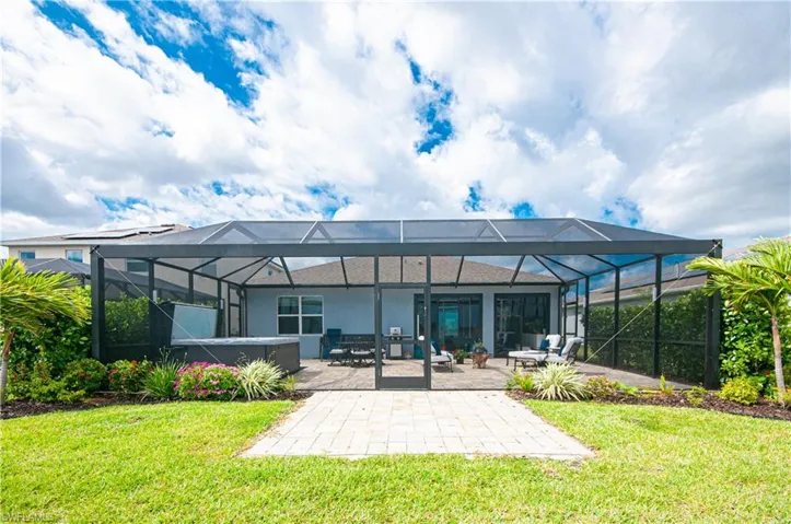 Expansive screened enclosure featuring a hot tub and paver patio