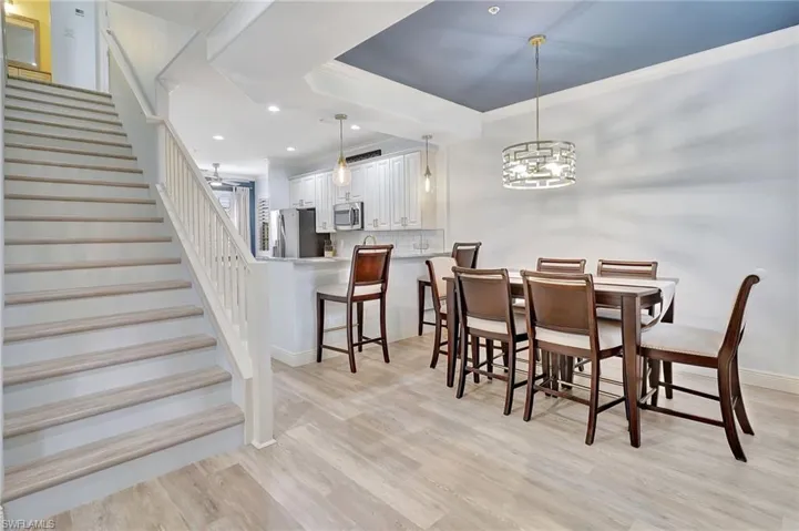 Dining space with a notable chandelier, light hardwood / wood-style flooring, crown molding, and a tray ceiling