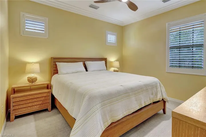 Carpeted bedroom with ceiling fan and ornamental molding