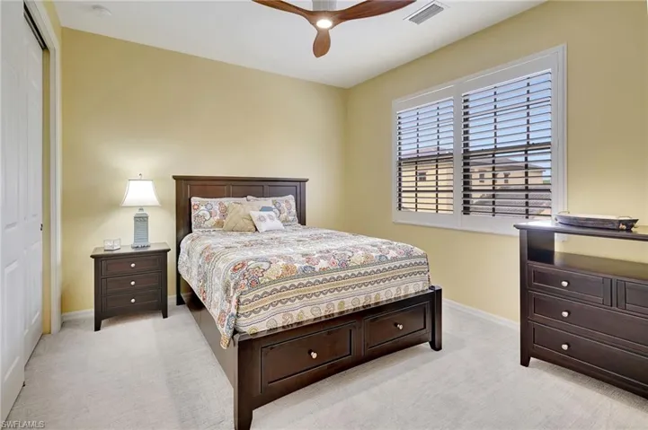 Bedroom with ceiling fan, a closet, and light carpet