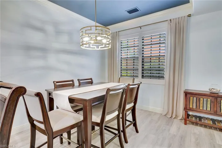 Dining space featuring light hardwood / wood-style flooring, crown molding, and a chandelier