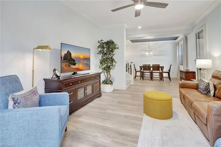 Living room with ceiling fan, light wood-type flooring, and ornamental molding
