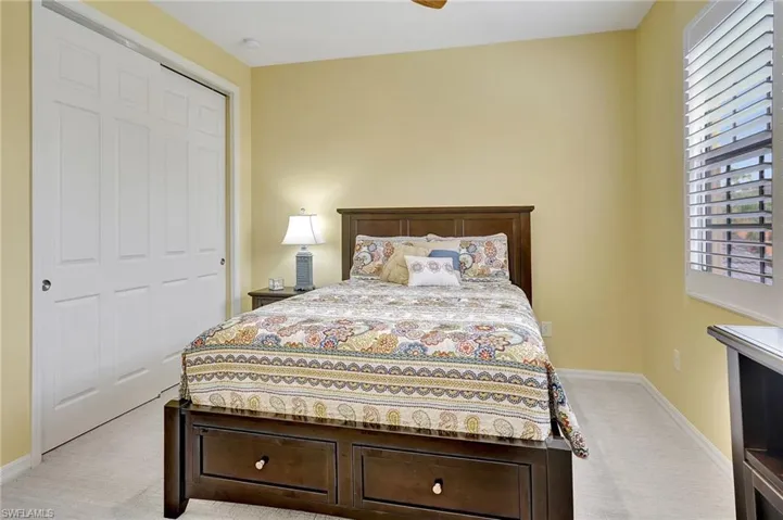 Carpeted bedroom with ceiling fan and a closet