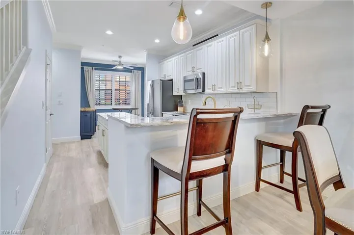 Kitchen featuring appliances with stainless steel finishes, a kitchen breakfast bar, kitchen peninsula, and light stone countertops