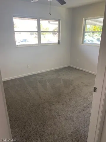 Carpeted empty room featuring plenty of natural light and ceiling fan