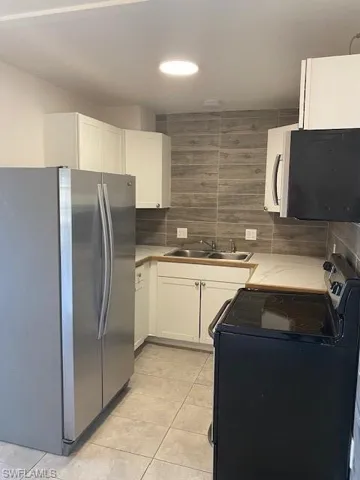 Kitchen with white cabinets, range, sink, and fridge