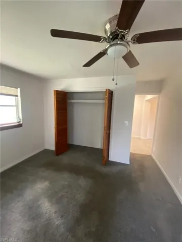 Unfurnished bedroom featuring dark colored carpet, ceiling fan, and a closet