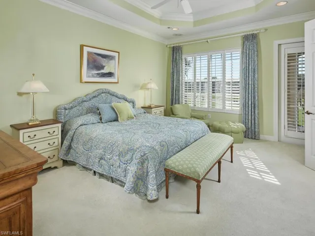 Another view of the primary suite, featuring a tray ceiling, crown molding and an abundance of natural light.