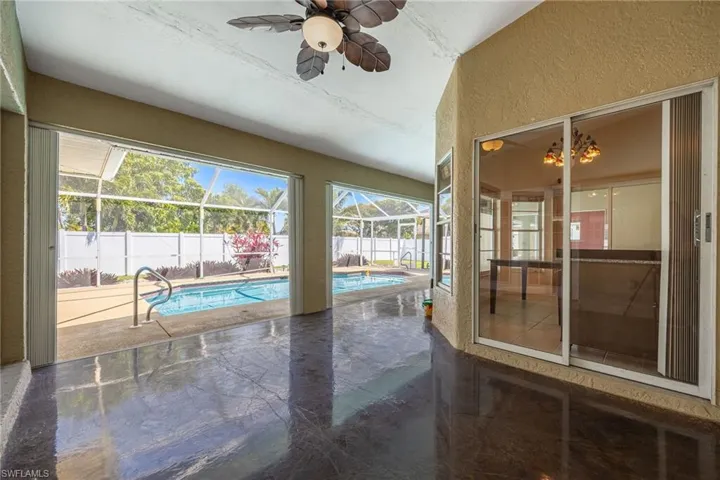 View of swimming pool featuring a fenced in pool, a patio, a fenced backyard, ceiling fan, and glass enclosure