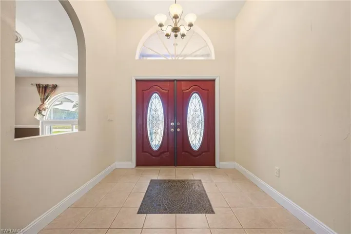 Foyer entrance with arched walkways, a notable chandelier, baseboards, and tile patterned floors