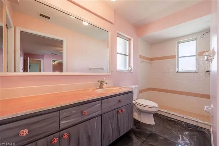 Full bathroom featuring vanity, visible vents, a tile shower, and toilet
