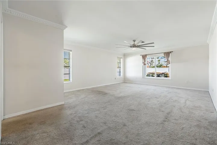 Carpeted spare room featuring crown molding, ceiling fan, and baseboards