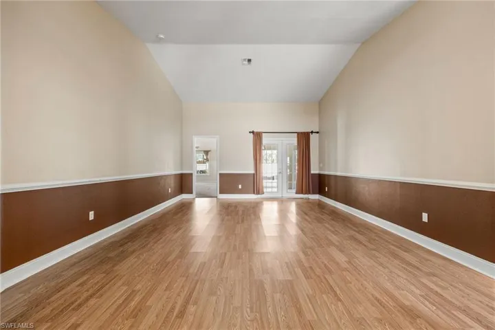 Empty room featuring light wood finished floors, baseboards, and lofted ceiling