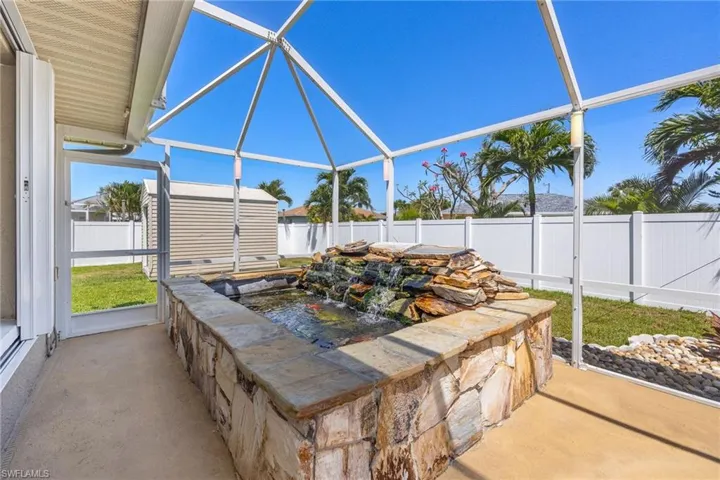 View of patio featuring a fenced backyard, an outdoor structure, a shed, and a lanai